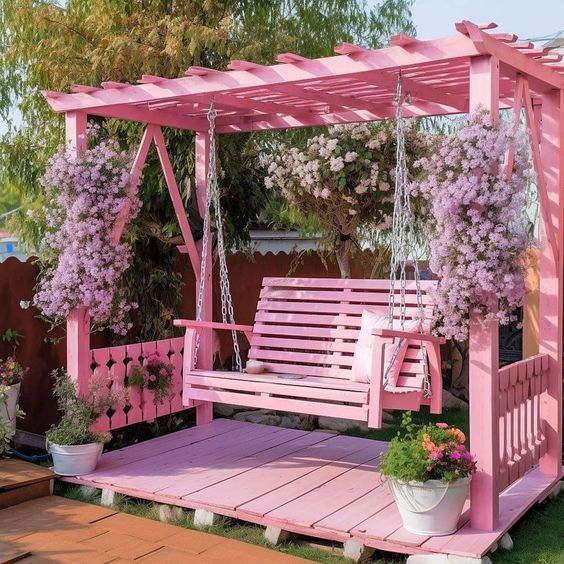 a pink arbor, deck and hanging chair on chain, lush pink blooms climbing up for a super cute and cozy look