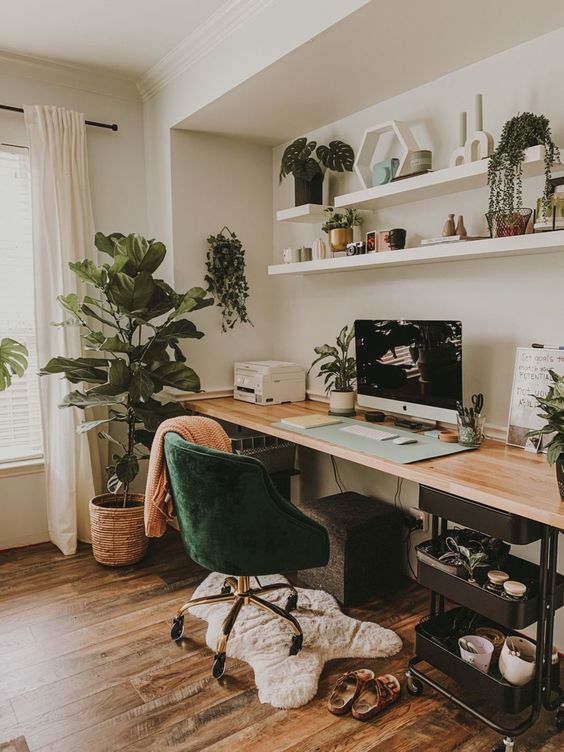 a pretty modern meets Scandinavian workspace with a desk, an IKEA cart for storing stuff, a potted plant, shelves with decor and a PC