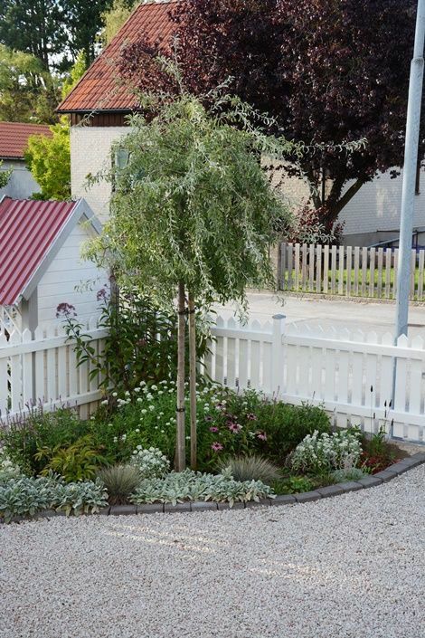 a pretty small corner garden with grasses, various blooms and a tree is a nice addition to any modern space