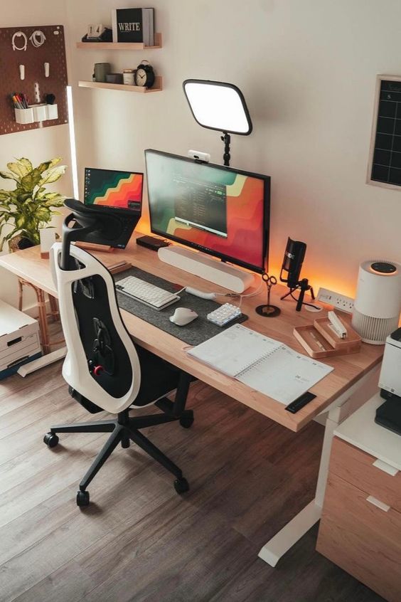 a pretty workspace with a desk and a chair, some devices and lamps, a pegboard with accessories, some ledges with decor