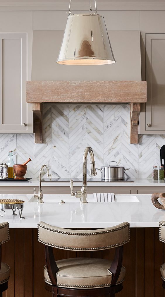 a refined tan kitchen with a stained kitchen island, white countertops and a chevron tile backsplash and some pendant lamps