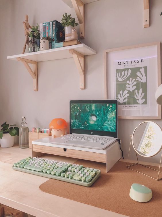 a Scandinavian working space with a laptop on a stand, some devices, a mirror, some accessories, books and plants