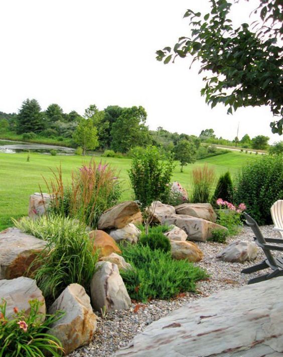 a simple and catchy rock garden with large rocks and greenery plus some blooms is a very bold solution