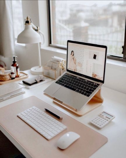 a small and laconic workspace with a laptop on a stand and white devices, a table lamp and some other stuff