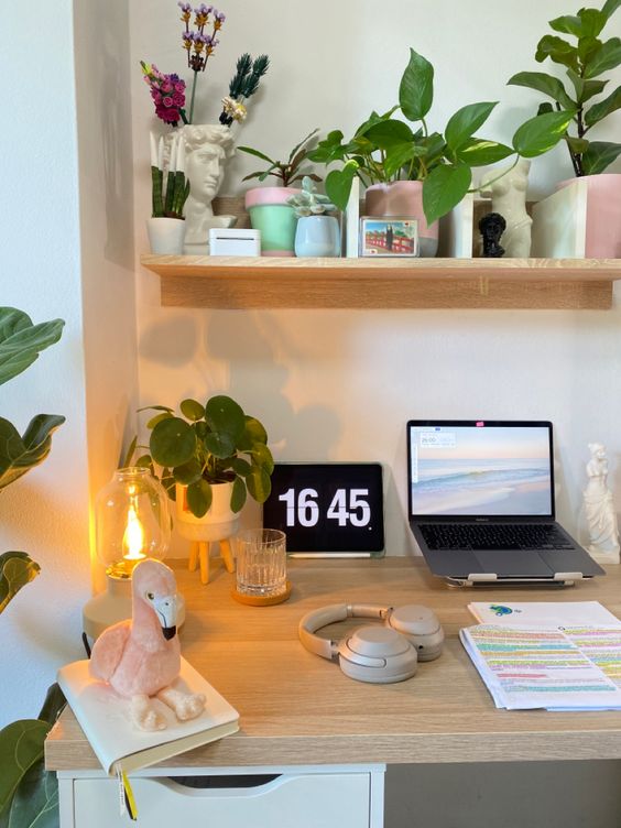 a small and pretty workspace with a laptop, a clock and lamps, potted plants and lovely decor is welcoming