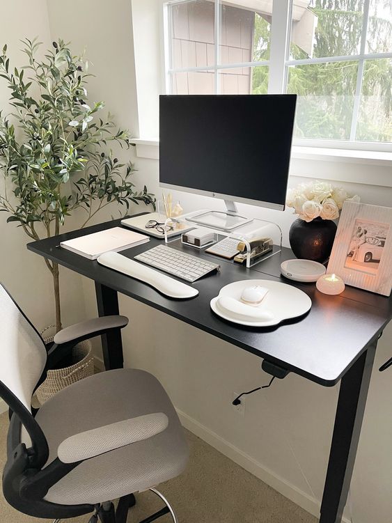 a small clean and minimal workspace with a black desk and a grey chair, a PC, some decor and a potted plant next to it