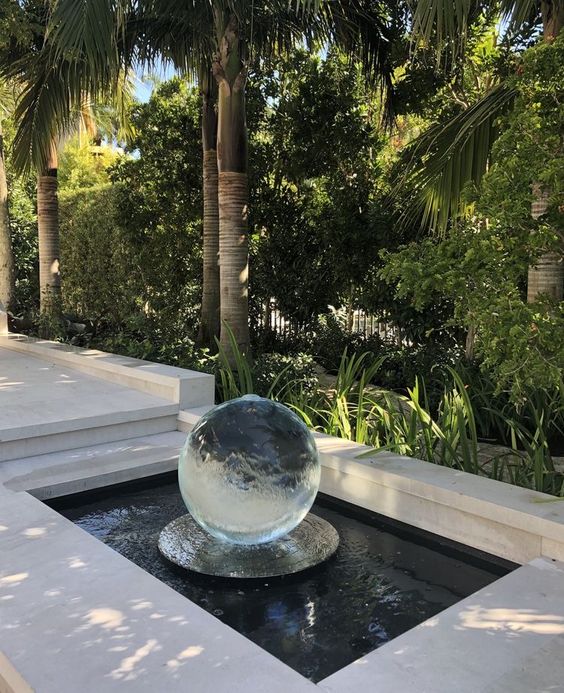 a small pond with a glass sphere is a beautiful and stylish decoration for a minimalist garden like this one