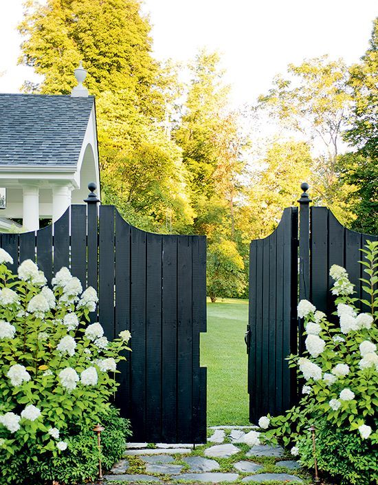 a stylish black fence and gate refreshed with white hydrangeas that contrast the fence and create a Scandi feel