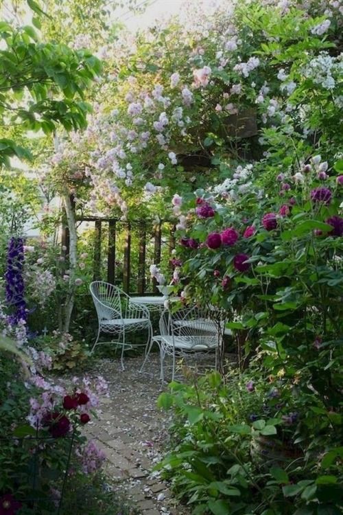 a tiny shady nook with blooming bushes and just flowers, greenery, refined metal garden furniture is a cute space to hide