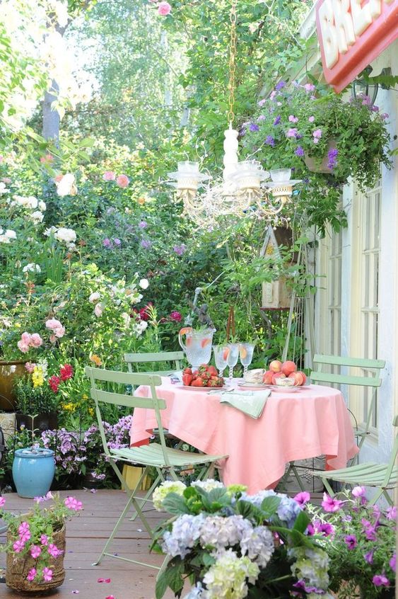 a vintage deck with folding garden furniture, lots of potted and planted flowers, a vintage chandelier