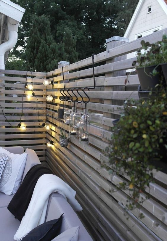 a weathered wood fence with lights and candle lanterns is a lovely solution for a Scandinavian backyard