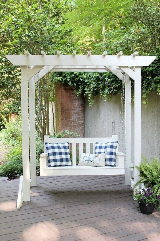 a white arbor with a bench on chain and some pillows can be placed anywhere you want as a frame is free-standing