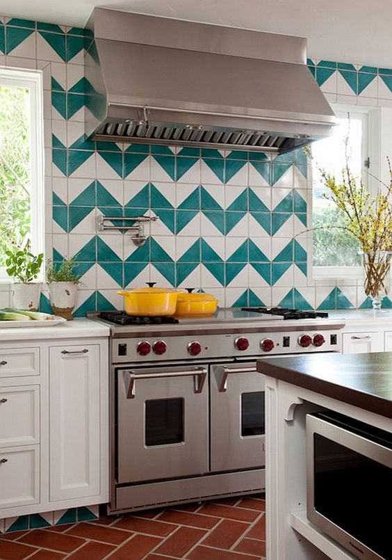 a white kitchen with a bold green and white chevron tile backsplash and stainless steel appliances is wow