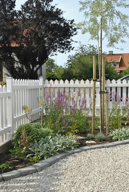 a white picket fence is classics, a corner flower bed with greenery and bodl blooms refresh the space