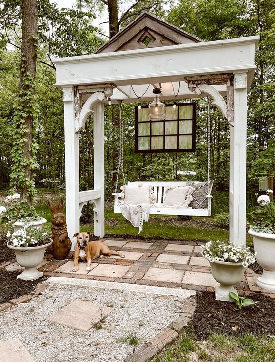 a beautiful vintage arbor with a pendant bench, lights and blooms around is a lovely pergola for any garden
