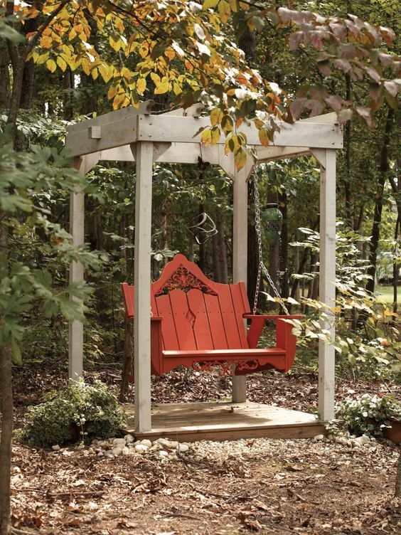 a whitewashed arbor frame with a hanging red wooden chair is a great idea, and this arbor can be covered with greenery or blooms