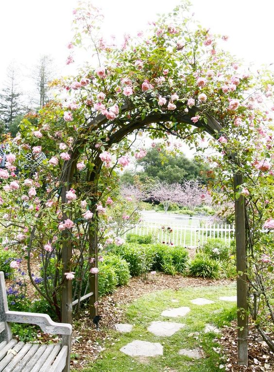 a wooden arched trellis covered with blush roses is a beautiful secret garden inspired piece for your outdoors