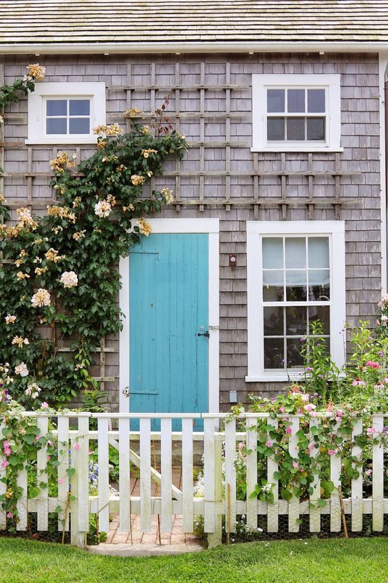 A simple and quite neutral house exterior is refreshed with pink bloom vines going up the trellis on one side.