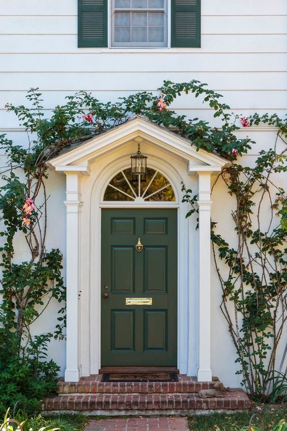 A dark green front door is perfectly echoed with matching vines going around it that highlight the entrance.