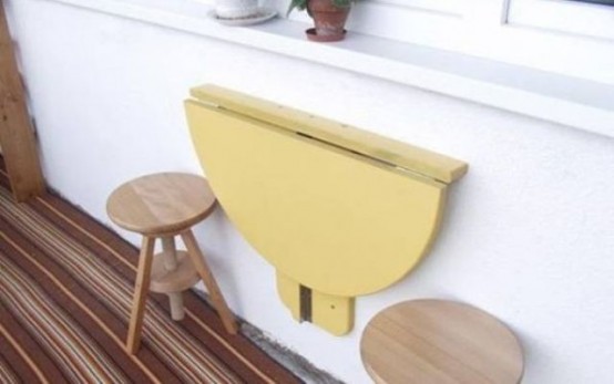 a bright yellow folding table can be attached to the wall in your balcony to hold anything you like and to serve food and drinks