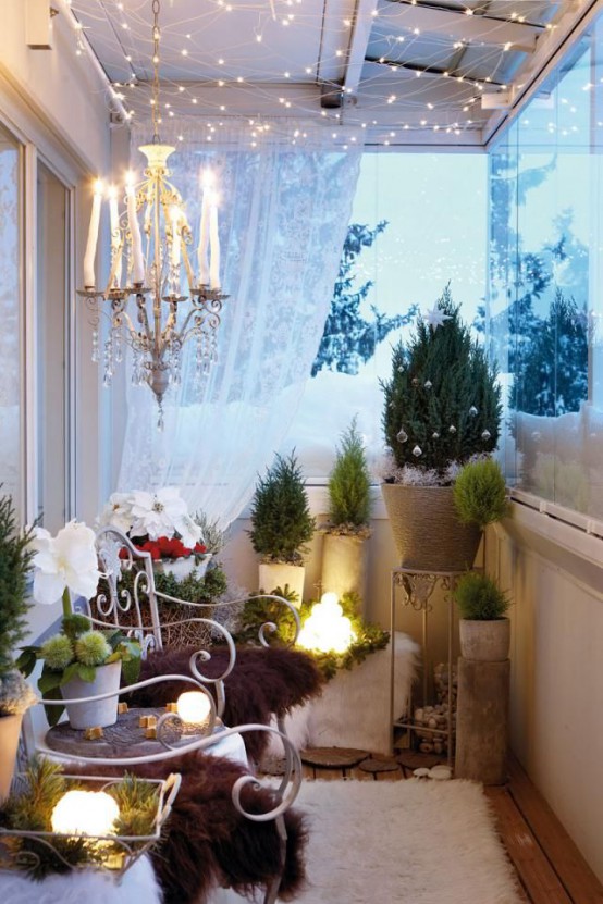 a cozy winter balcony done with mini Christmas trees, lots of faux fur, a crystal chandelier and lots of lights