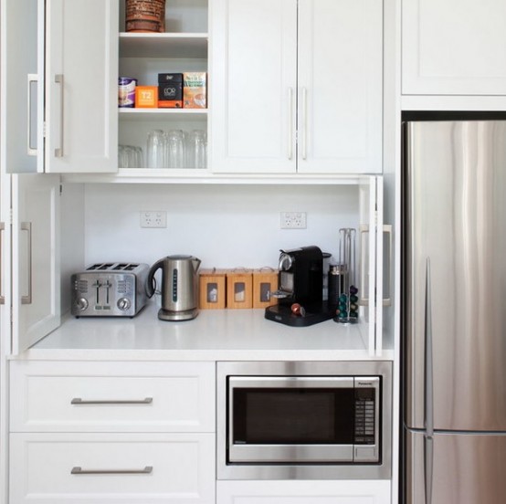 a cabinet with folding doors, a coffee machine, a kettel and a toaster plus mugs and sugar is a perfect breakfast station