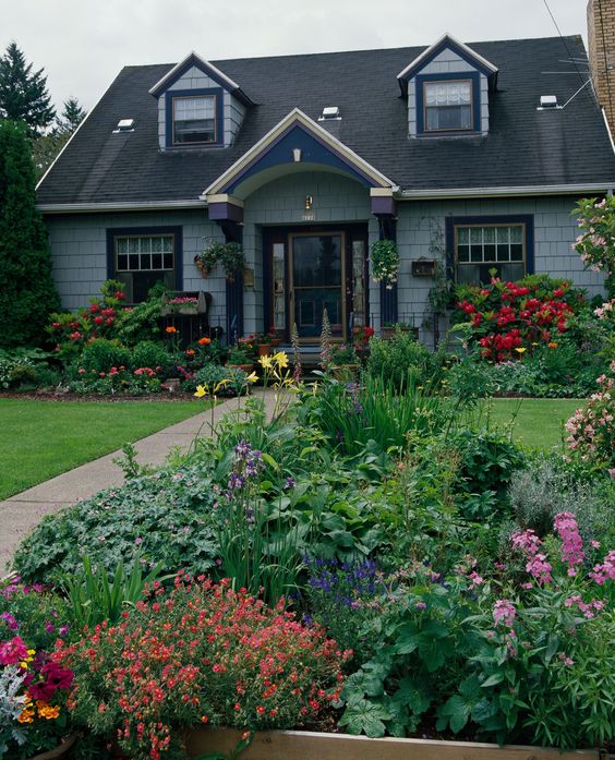 Flower beds along the house and the fence, with various types of greenery and blooms add interest to the front yard and refreshes the look of the clean green lawn.