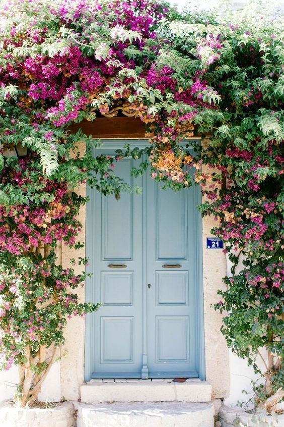 A jaw-dropping space with pale blue doors and bright flowers and greenery over the door to add even more color. 