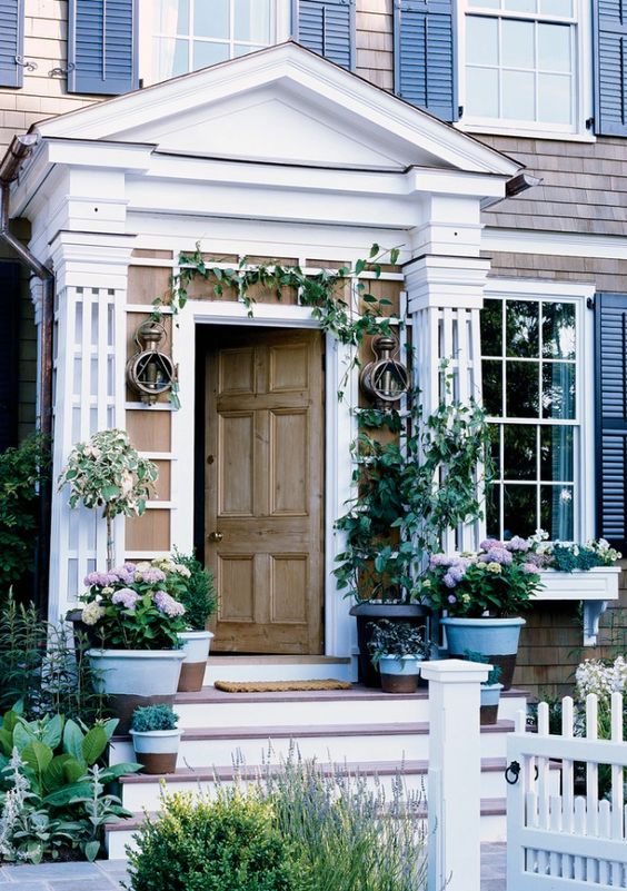 Potted blooms and greenery, green vines over the door make the porch fresh, elegant and chic.