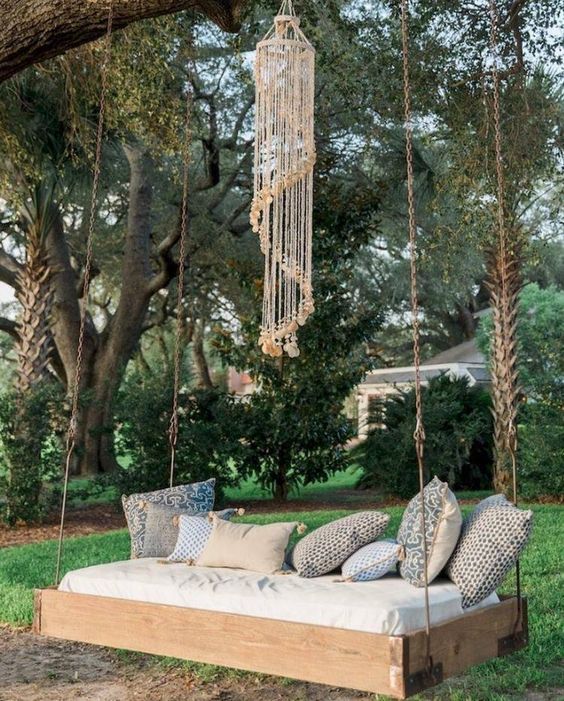 hang a swing on a tree, with a dream catcher and boho pillows to create your outdoor space for having a rest and sleeping
