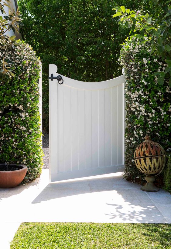 lush green and white flourishing vines completely covering the fence give it a very chic, fresh and unusual look, and a curved gate finishes it off