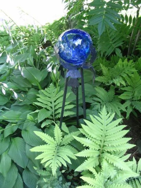 lush greenery accented with a bold blue glass ball on a stand looks prettier and cooler and such a ball can accent the space
