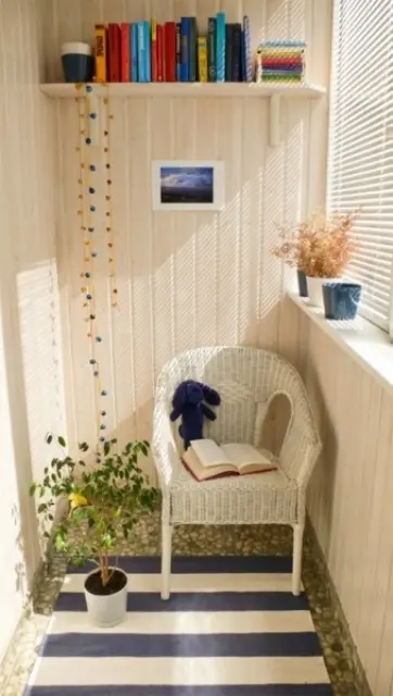 a small Scandinavian balcony with a striped rug, a woven chair, a bookshelf, a potted plant and colorful books