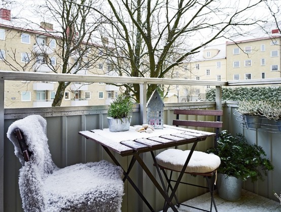 a small Scandinavian balcony with folding furniture, sheepskins for more coziness and a bit of potted greenery