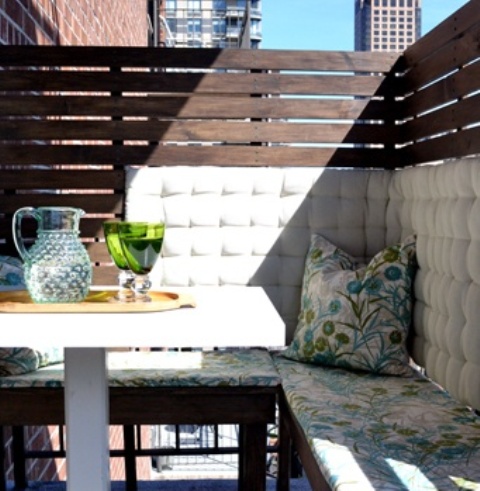 a cozy small balcony with a privacy screen, a corner bench with storage, some pillows and a coffee table is a lovely nook