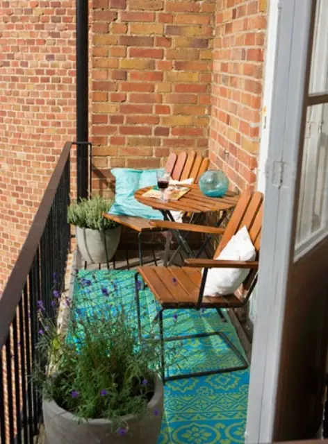 a small and bright balcony with a couple of chairs and a side table, a bright rug, pillows and potted plants is a lovely and bold space