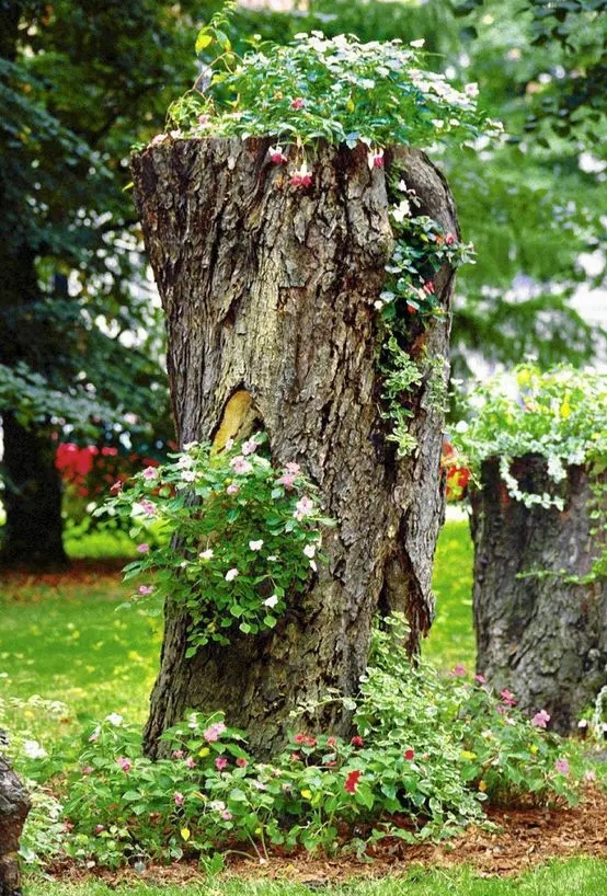 tree stumps with greenery and bright blooms plus greenery and blooms around are a catchy and super natural decoration for any garden