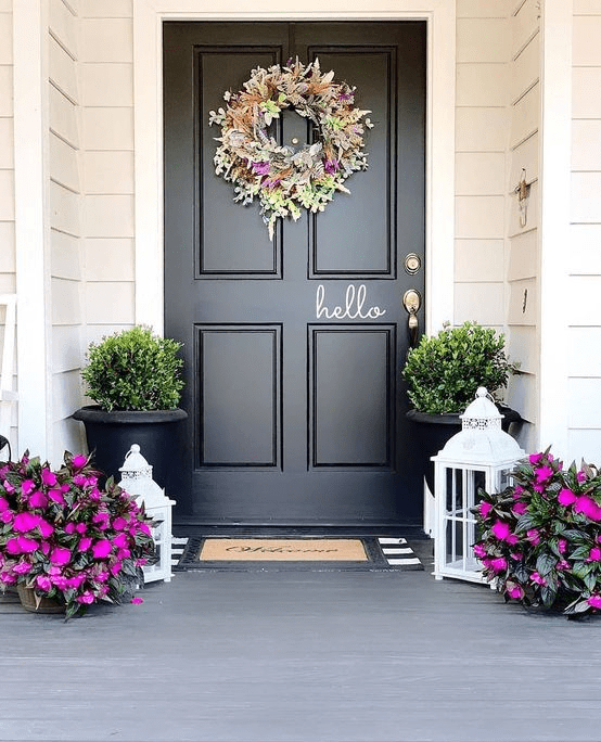 a bright spring porch done with hot pink blooms in pots, with a bright and textural floral and greenery wreath and greenery in pots