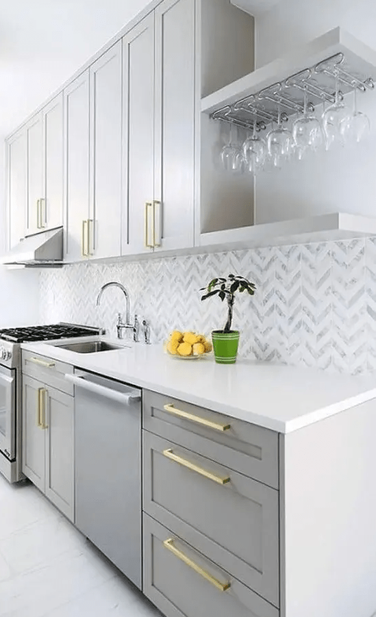 a contemporary with dove grey cabinets, a chevron tile backsplash and gold handles looks very chic and elegant