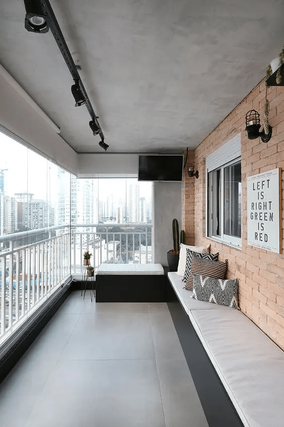 a cool modern balcony with a built-in upholstered bench along the whole wall, a small seat, potted plants and lamps