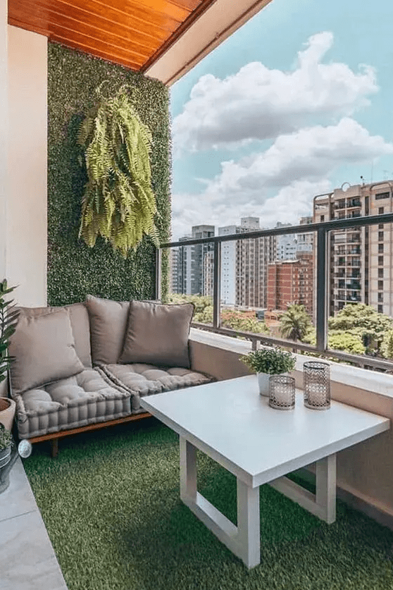 a cool modern balcony with a faux living wall and floor, a cool loveseat, potted greenery, a small table with greenery and candles