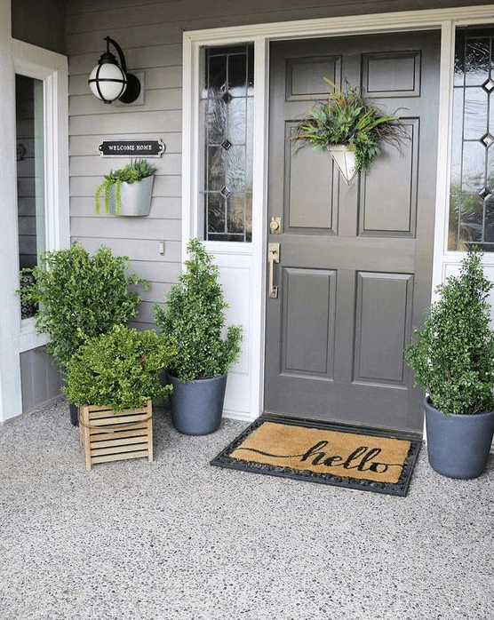 a fresh spring porch decorated only with greenery in pots and crates and with greenery on the door