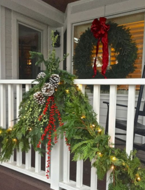 lush evergreen garlands with berries, pinecones, lights and a matching evergreen wreath with a large red bow