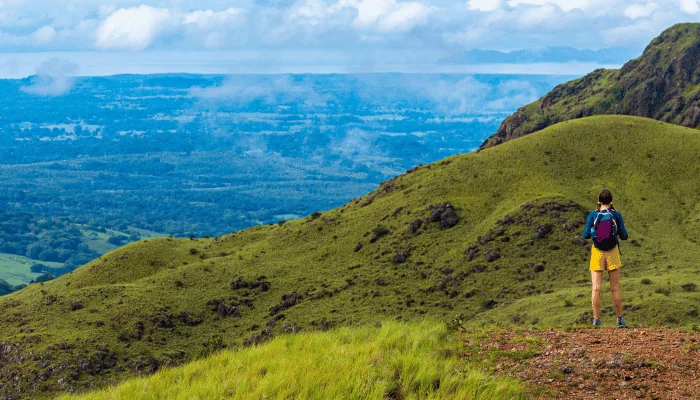 A backpacker girl admires the skyline of Costa Rica's Cerro Pelado mountains during a sunny day