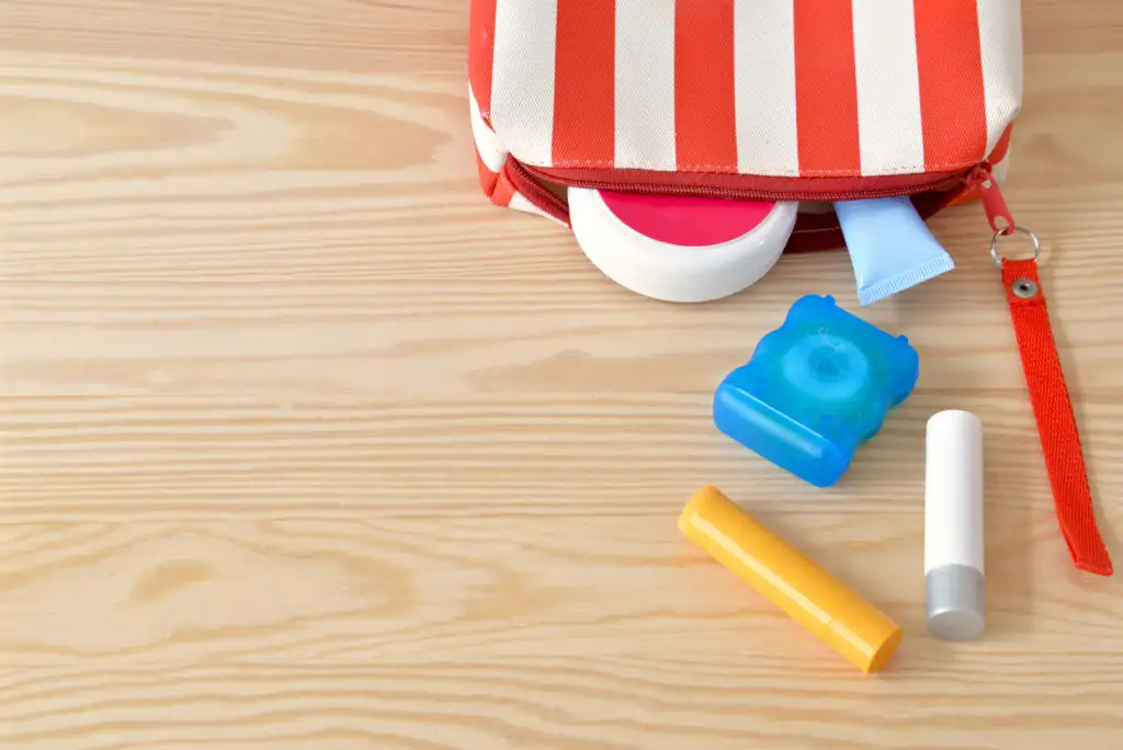 Toiletries bag spilled across wooden backdrop