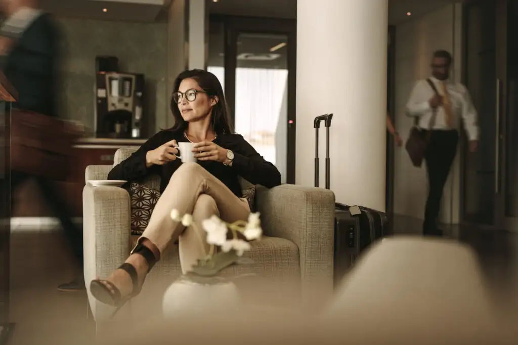 Woman drinking coffee in an airport lounge, looking away from the camera