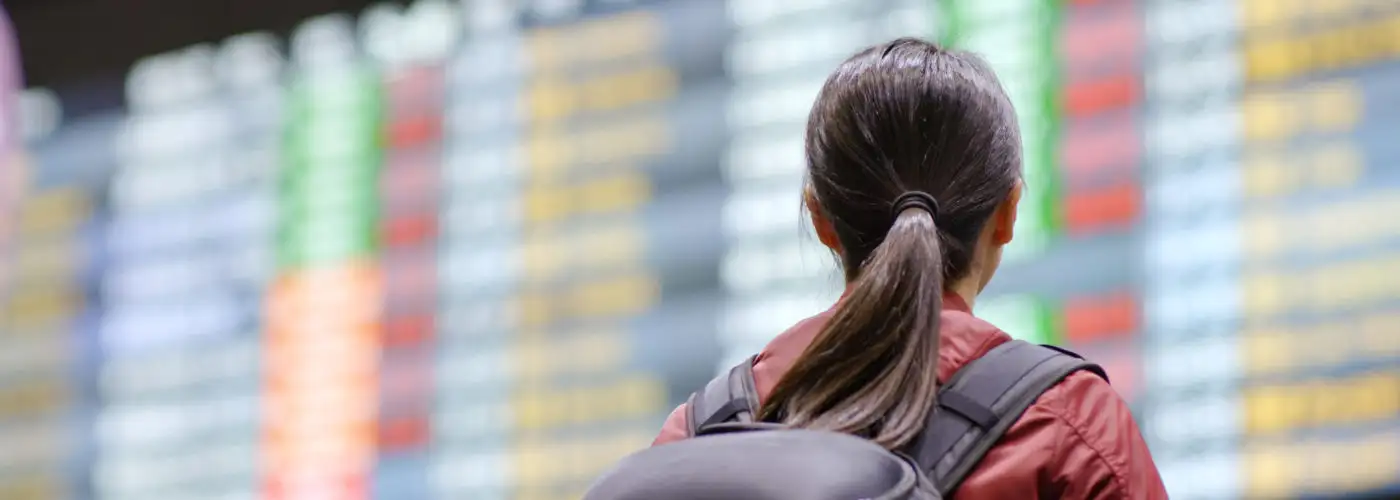 Woman with backpack reading the arrivals board at an airplane