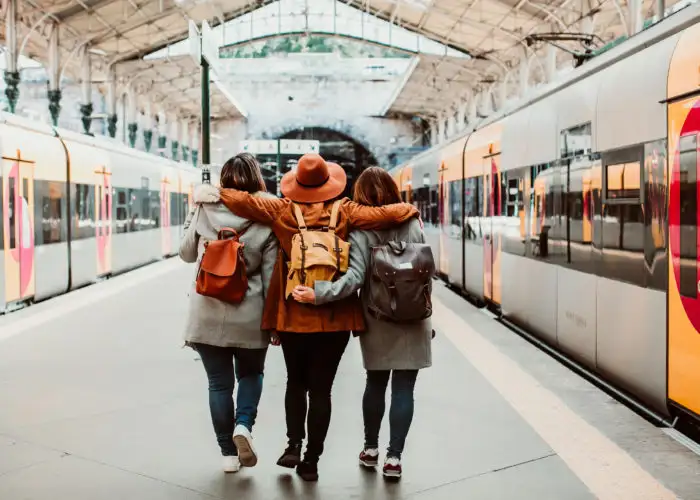 Three friends facing away from camera at train station