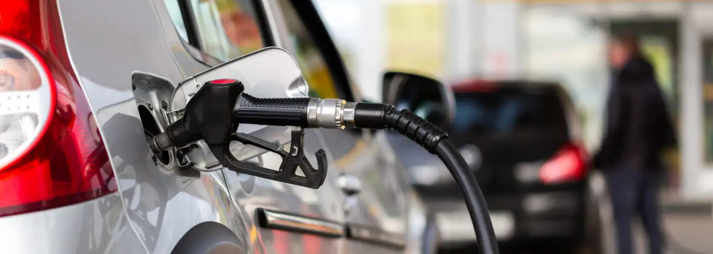 Close up of a gas pump attached to a car as it refuels at a gas station