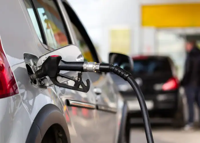 Close up of a gas pump attached to a car as it refuels at a gas station